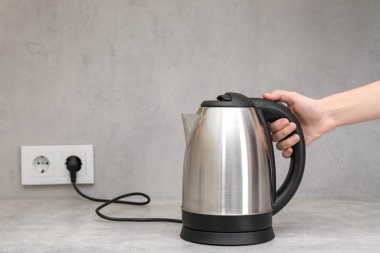 Mutfakta elektrikli su ısıtıcısı olan kadın, yakın plan. Metin için boşluk