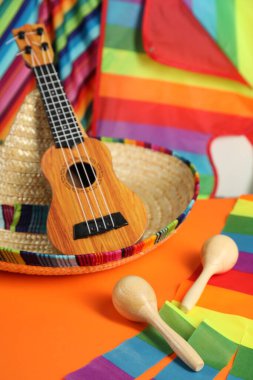 Meksika şapkası, ukulele ve marakas turuncu masada, yakın plan.