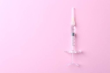 Kozmetoloji. Pembe arka planda tıbbi şırınga, üst manzara. Metin için boşluk