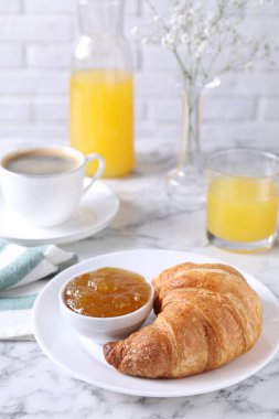 Lezzetli bir kahvaltı. Taze kruvasan ve reçel beyaz mermer masada.