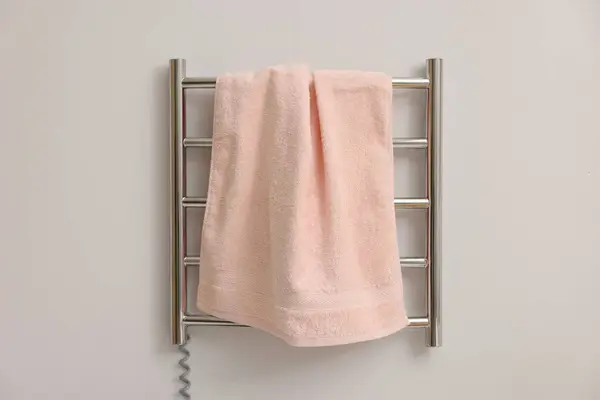 Heated rail with pink towel on white wall