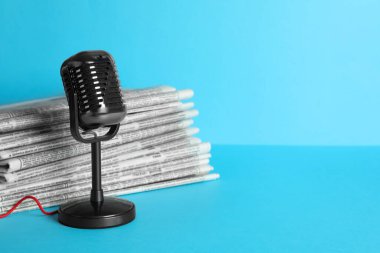 Gazeteler ve açık mavi arka planda klasik mikrofon, mesaj için yer. Gazeteci işi.