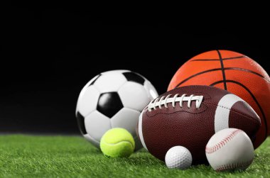 Siyah arkaplana karşı yeşil çimenler üzerinde birçok farklı spor topu, metin için boşluk