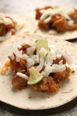 Gri desenli masada sebzeli, etli ve limonlu lezzetli tacolar, yakın plan.