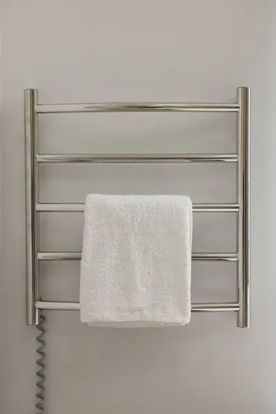 Heated rail with towel on white wall in bathroom
