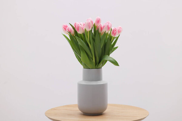 Beautiful bouquet of fresh pink tulips on table against light background