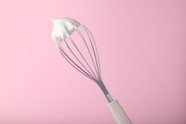 Pembe arka planda çırpılmış yumurta beyazı çırpın.