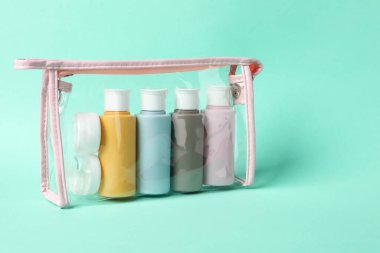 Turkuaz arka planda plastik poşette kozmetik seyahat seti. Metin için boşluk