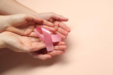 Göğüs kanseri farkındalığı. Bej arka planda pembe kurdeleli kadınlar, üst manzara. Metin için boşluk