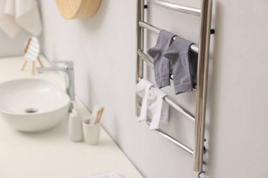 Banyoda beyaz duvarda çorapları olan ısıtmalı havlu rayı.