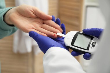 Diyabet. Doktor kan şekerini klinikte glukometreyle ölçüyor.