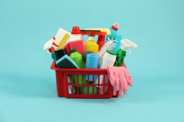 Açık mavi arka planda plastik sepette farklı temizlik ürünleri