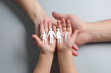 Gri arka plan, üst görünüm üzerinde kağıt aile figürleri tutan ebeveynler ve çocuklar