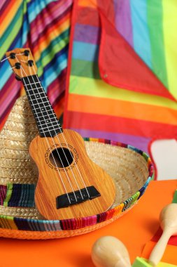 Meksika şapkası, ukulele ve marakas turuncu masada, yakın plan.
