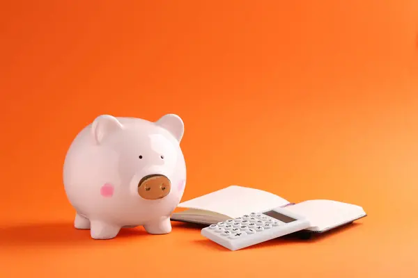 Financiële Besparingen Piggy Bank Notebook Rekenmachine Oranje Achtergrond — Stockfoto