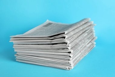 Açık mavi arka planda bir yığın gazete. Gazeteci işi.