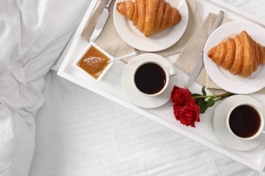 Yatakta servis edilen lezzetli kahvaltı. Taze kruvasanlar, tepside kahve ve bal, üst manzara. Metin için boşluk
