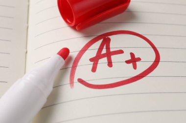 Okul derecesi. Kırmızı harf A. Not defteri kağıdında artı işareti var. Yakın plan.