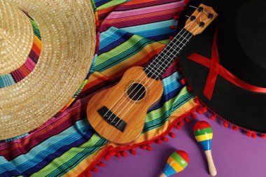 Meksika sombrero ve siyah Flamenko şapkalar, ukulele ve marakas ile mor masa üzerinde düz konum