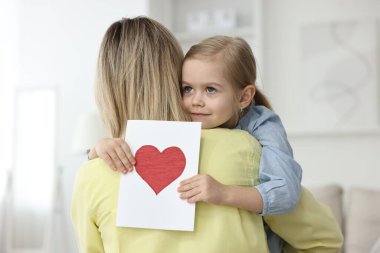 Küçük kızı evde annesini tebrik kartıyla tebrik ediyor. Anneler Günün kutlu olsun.