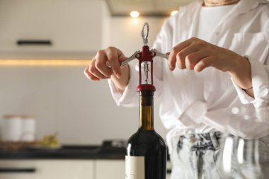 Kadın şarap şişesini açarken kapalı alanda tirbuşonla, yakın plan. Metin için boşluk