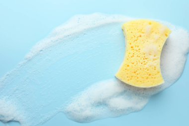 Açık mavi arka planda köpüklü sarı sünger, üst görünüm