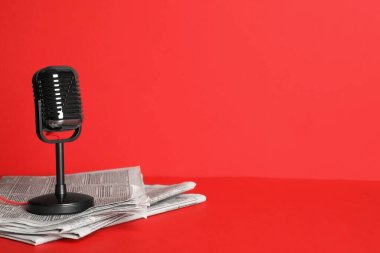 Gazeteler ve eski mikrofon kırmızı arka planda, mesaj için yer var. Gazeteci işi.