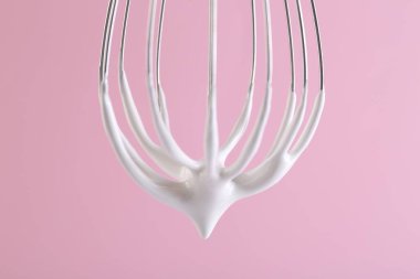 Pembe arka planda krem şantili çırpma çırpma, yakın plan.