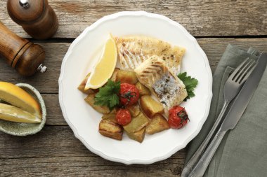 Tahta masada servis edilen sebzelerle pişirilmiş lezzetli bir morina balığı.