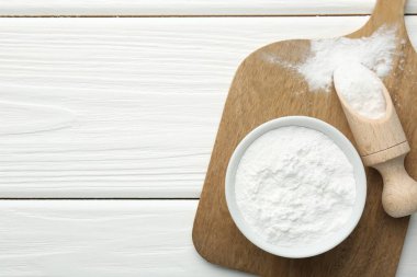 Kabın içinde kabartma tozu ve beyaz ahşap masa üzerinde kepçe, üst manzara. Metin için boşluk