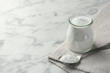 Kavanozda kabartma tozu ve beyaz mermer masada kaşık, metin için boşluk