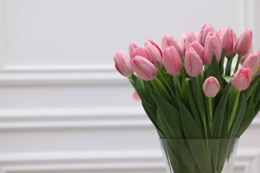 Beyaz duvarın yanında güzel pembe laleler, yazı için yer var.