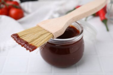 Marinade in jar and basting brush on white table, closeup clipart