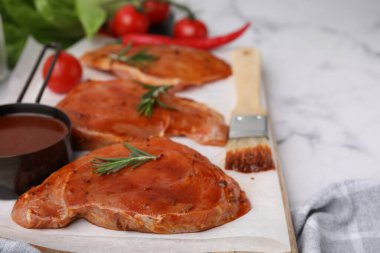 Çiğ marine edilmiş et, biberiye ve beyaz mermer masada fırça, yakın plan.