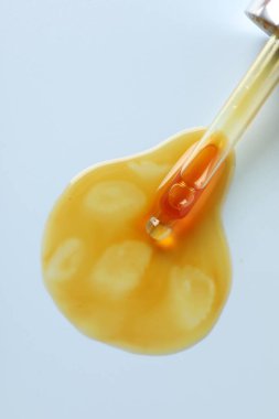 Açık gri arkaplandaki pipetten damlayan nemlendirici serum, üst görünüm