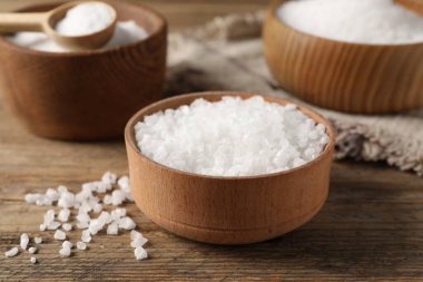 Farklı bulaşık takımlarındaki doğal tuz ahşap masada, yakın plan.