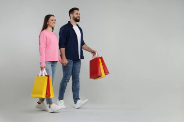 Gri arka planda alışveriş torbaları olan mutlu bir çift. Metin için boşluk