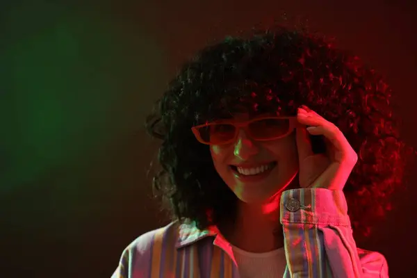 ネオンライトの色の背景にポーズサングラスの美しい若い女性 — ストック写真