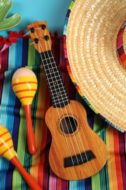 Meksika şapkası, marakas ve ukulele açık mavi masada, düz yatıyordu.