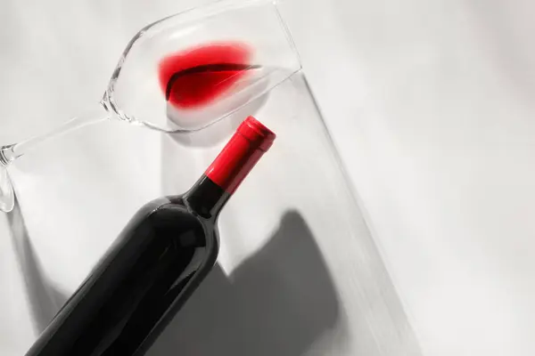 Bottle of expensive red wine and wineglass on light background, top view. Space for text