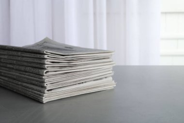 Gri masadaki gazete yığını, mesaj için yer. Gazeteci işi.