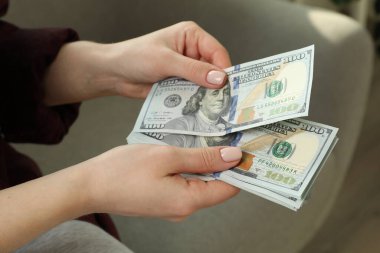 Para değişimi. Bulanık arka planda dolar banknotları sayan kadın, yakın plan