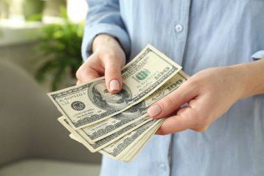 Para değişimi. Bulanık arka planda dolar banknotları sayan kadın, yakın plan