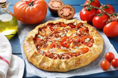 Mavi ahşap masada domates ve peynirli lezzetli bir galet, yakın plan.