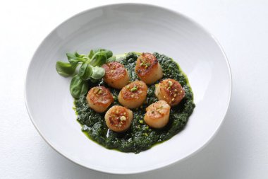 Lezzetli soslu leziz kızarmış deniz tarakları ve beyaz masada mısır salatası, yakın plan.