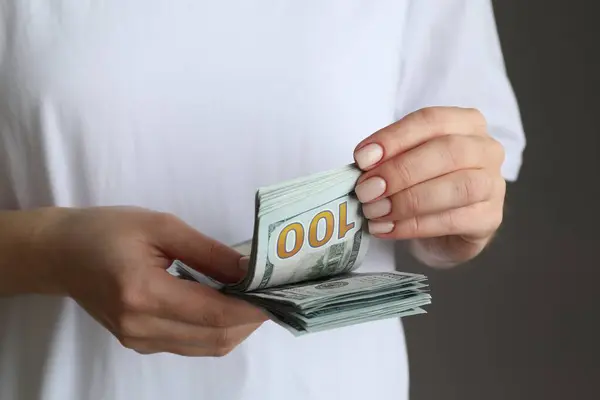 Utbyte Pengar Kvinnan Räknar Dollarsedlar Grå Bakgrund Närbild — Stockfoto