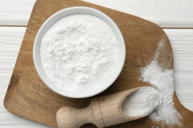 Kabın içinde kabartma tozu ve beyaz ahşap masa üzerinde kepçe, üst görünüm