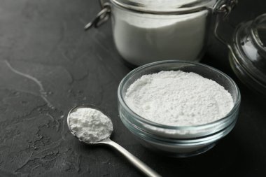 Kabın içinde kabartma tozu, kavanoz ve kaşık siyah desenli masa, yakın çekim. Metin için boşluk