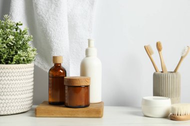Farklı banyo aksesuarları ve kişisel bakım ürünleri beyaz duvara karşı açık mermer masa üzerinde