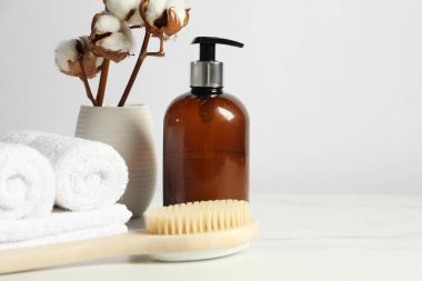 Farklı banyo aksesuarları ve vazodaki pamuk çiçekleri beyaz duvara karşı, yazı için yer